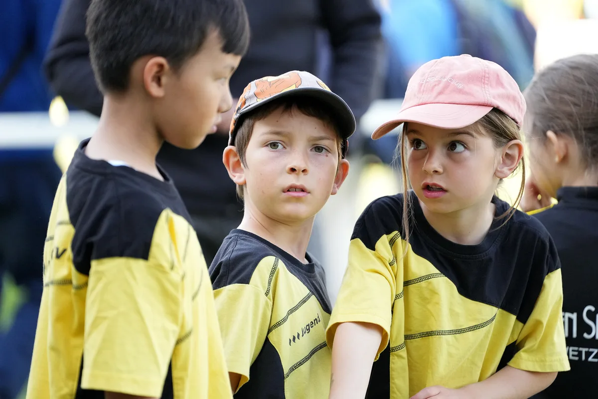 Drei Kinder in gelb-schwarzen T-Shirts sprechen miteinander.